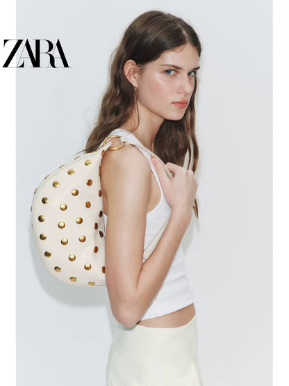 Bolsa feminina ZARA, lançamento da coleção verão 2026, com detalhes em rebites e zíper com argola metálica, modelo ombro, código 6094810 850.